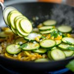 Zucchine che cuociono in padella con menta e cipolla.