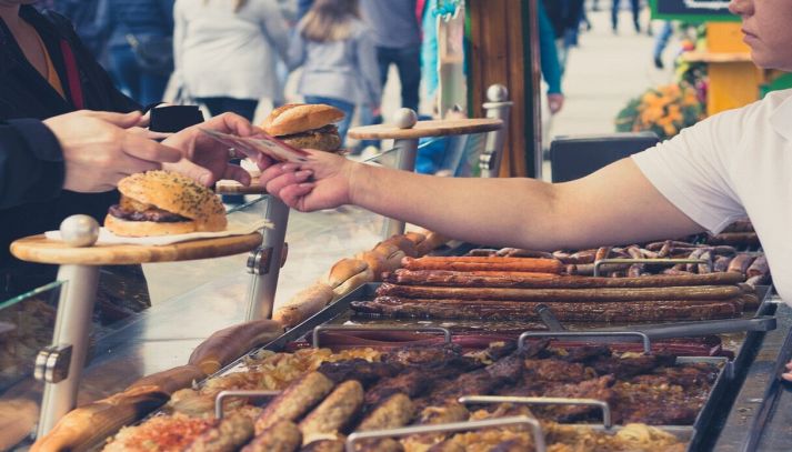 persona che acquista cibo salsiccia alla griglia ad una fiera