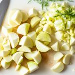 Finocchi tagliati a spicchi su tagliere.