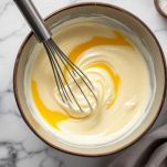 Ciotola con panna, uova e spezie mescolate.