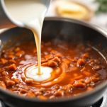 Ragù che sobbolle lentamente in padella.