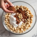 Cacao, zucchero e nocciole versati nella ciotola coi biscotti.