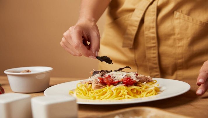 donna decora spaghetti con pomodoro tonno e basilico