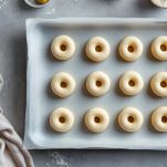 Ciambelle crude disposte su piano infarinato a riposo.