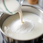 Pentolino con latte e zucchero sul fuoco a fiamma bassa.