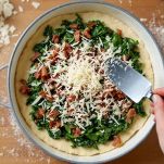 Ripieno di spinaci e pancetta distribuito sulla base di pasta in tortiera.