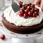 Strati di torta al cacao farciti con panna e ciliegie.