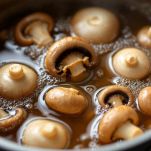 Funghi shiitake in cottura in pentolino con brodo e condimenti giapponesi.