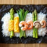 Foglio di alga nori con riso e ingredienti disposti per futomaki.