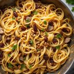 Bucatini mescolati con sarde e condimento nel tegame.