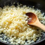 Riso con cipolla, zafferano e brodo caldo in padella.