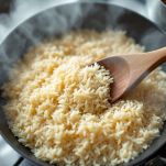 Riso che cuoce con brodo caldo aggiunto poco alla volta.