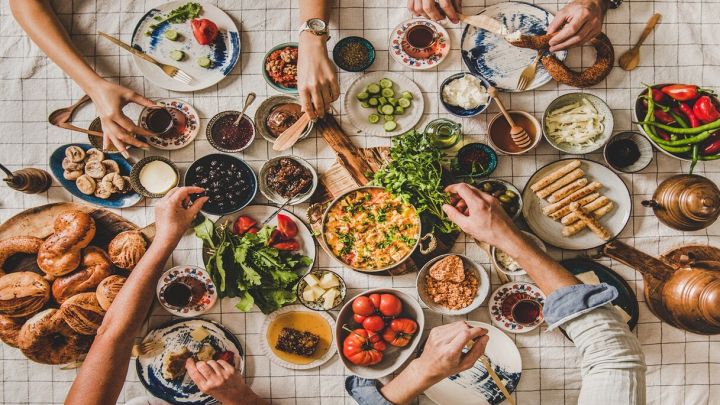 tavola apparecchiata con mani che prendono cibo