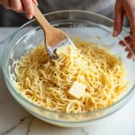 Vermicelli mescolati con uova e formaggio in ciotola capiente.