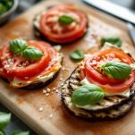 Fette di melanzane farcite con pomodoro, scamorza e basilico.