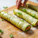 Mani che arrotolano melanzane grigliate con farcitura.