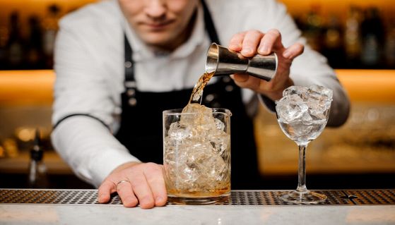 barman con camicia bianca prepara cocktail