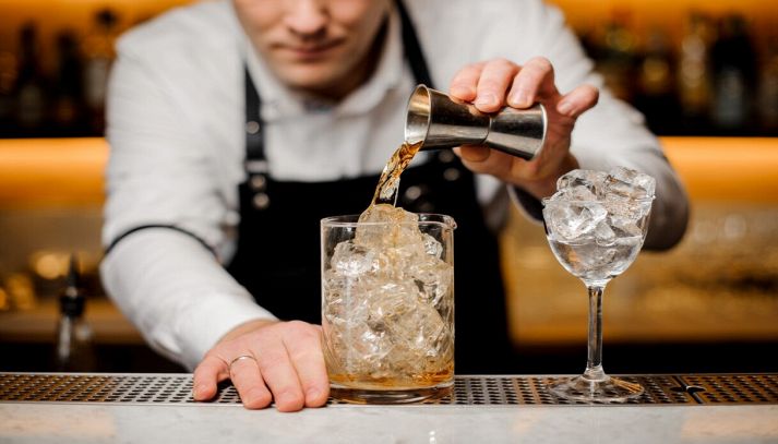 barman con camicia bianca prepara cocktail