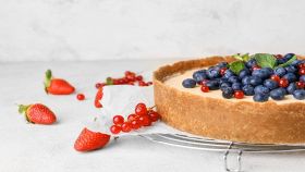 cheesecake con mirtilli e fragole su piano bianco