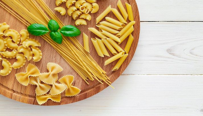 formati di pasta vari su tagliere di legno