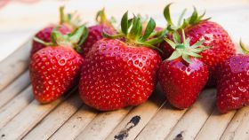 Fragole di varietà e dimension diverse su un piano di legno