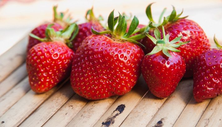Fragole di varietà e dimension diverse su un piano di legno