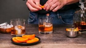 uomo prepara cocktail con arancia