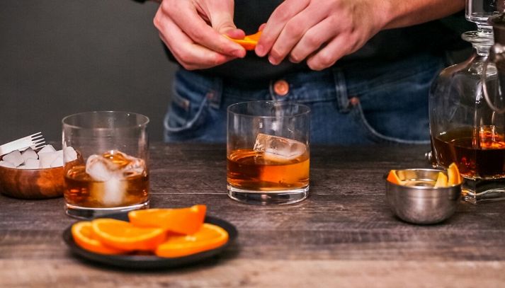 uomo prepara cocktail con arancia