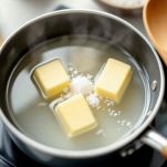 Burro sciolto con acqua e sale in tegame a ebollizione