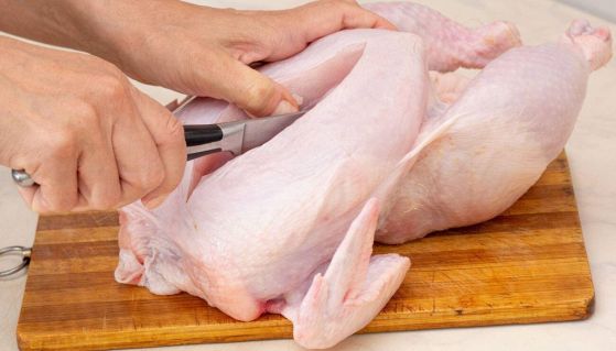 Donna che taglia il pollo