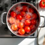 Pomodori pelati e tagliati su tagliere.