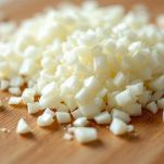 Coltello che trita cipolla bianca su un tagliere di legno