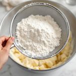 Farina setacciata in una ciotola con impasto.