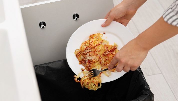 Donna butta piatto di pasta nella spazzatura