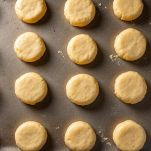 Cerchi di impasto in cottura su teglia con carta forno.