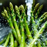 Mani che sciacquano gli asparagi nel lavello