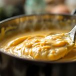 Frusta che mescola besciamella cremosa nel tegame