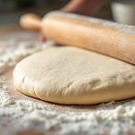 Pasta stesa con mattarello su piano infarinato.