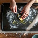 Mani che ungono una teglia da forno