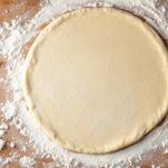 Mattarello che stende la pasta su un piano infarinato