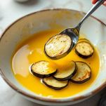 Ciotola con uova sbattute e melanzane immerse