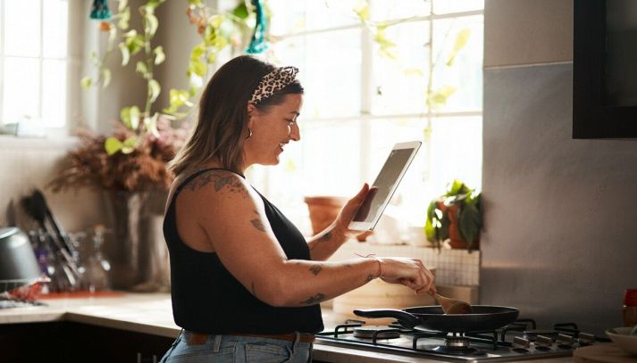 Donna cucina leggendo una ricetta dal tablet