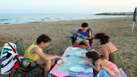 Famiglia mangia sulla spiaggia al tramonto