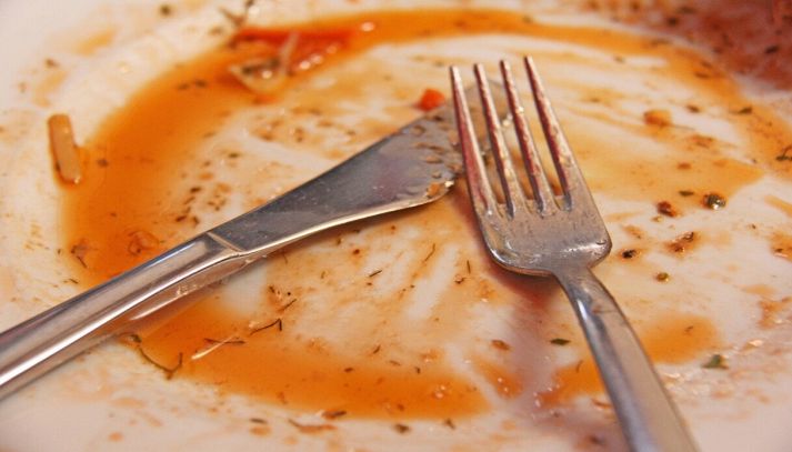 Piatto sporco dopo mangiato con forchetta e coltello