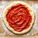 Impasto steso su teglia con salsa di pomodoro