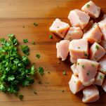 Mani che tagliano il pollo a piccoli bocconcini