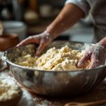 Mani che lavorano un impasto morbido sul piano