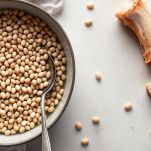 Ciotola con fagioli secchi e pentola con fagioli in cottura