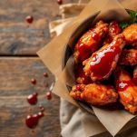 Ali di pollo servite con salsa barbecue.