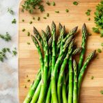 Punte di asparagi tagliate su tagliere.